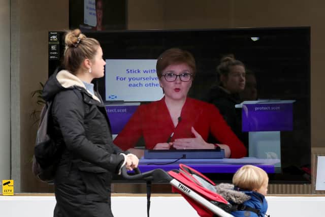 A member of the public walks past a TV screen at The Sound Counsel in Edinburgh as First Minister Nicola Sturgeon takes part in a virtual sitting of the Scottish Parliament after a range of new restrictions to combat the rise in coronavirus cases came into place in Scotland. Picture: Andrew Milligan/PA Wire