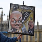 A demonstrator holds a placard showing Boris Johnson and his former special adviser Dominic Cummings outside the UK Parliament (Picture: Justin Tallis/AFP via Getty Images)