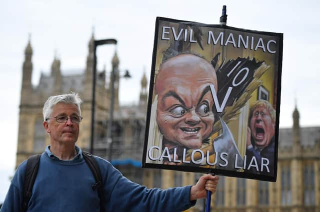 A demonstrator holds a placard showing Boris Johnson and his former special adviser Dominic Cummings outside the UK Parliament (Picture: Justin Tallis/AFP via Getty Images)