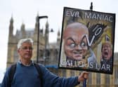 A demonstrator holds a placard showing Boris Johnson and his former special adviser Dominic Cummings outside the UK Parliament (Picture: Justin Tallis/AFP via Getty Images)