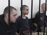 Two British citizens Aiden Aslin, left, and Shaun Pinner, right sit behind bars in a Russian-backed courtroom in Donetsk.