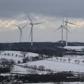 Wind turbines spinning atop snow covered hills around Avonbridge near Falkirk in Scotland.
