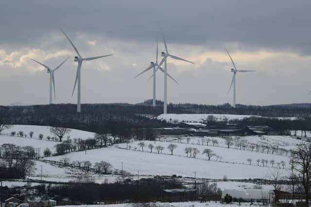 Wind turbines spinning atop snow covered hills around Avonbridge near Falkirk in Scotland.