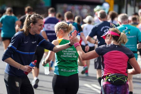 Jill Scott MBE former English professional footballer interacts with runners at the Lucozade Gel Station during the 2022 TCS London Marathon.