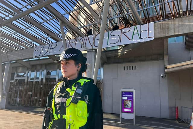 A Police Scotland officer outside the Scottish Parliament building as the protest takes place. Picture: Lisa Ferguson