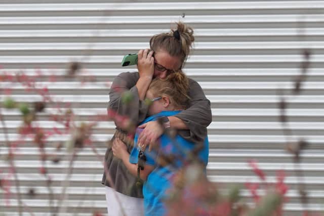 A woman cries and hugs a young girl while on the phone outside the Willie de Leon Civic Center where grief counseling will be offered in Uvalde, Texas, on May 24, 2022. 
The attack in Uvalde, Texas -- a small community about an hour from the Mexican border -- is the latest in a spree of deadly shootings in America, where horror at the cycle of gun violence has failed to spur action to end it. (Photo by Allison dinner via Getty Images)
