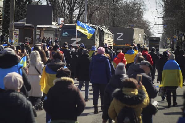 People with Ukrainian flags walk towards Russian army trucks during a rally against the Russian occupation in Kherson. Picture: AP Photo