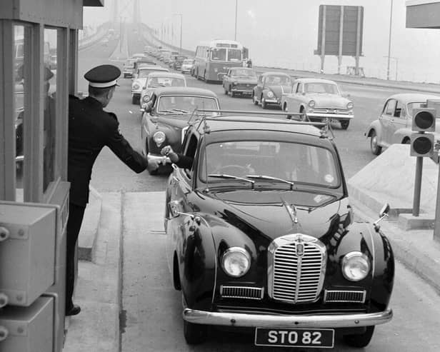 A driver pays the toll at the Forth Road Bridge in 1964, handing the money to a uniformed collector ... and how cars have changed too!