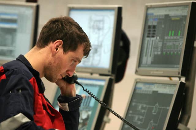 A technician listens on the phone while monitoring equipment in the main control room of the liquified natural gas (LNG) plant.