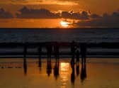 People walk along Kuta beach during sunset on the Indonesian resort island of Bali.
