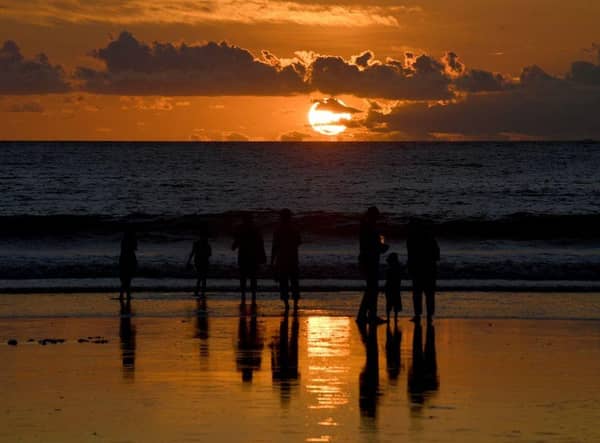 People walk along Kuta beach during sunset on the Indonesian resort island of Bali.