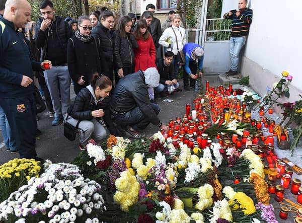 People light candles at a memorial outside the nightclub Colectiv in Bucharest in 2015, after a fire broke out, ultimately killing 64 people.