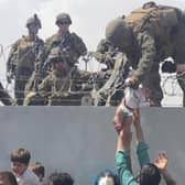 A US Marine lifts a baby over a barbed wire fence at Kabul's international airport as people scrambled to escape the advance of the Taliban in August last year (Picture courtesy of Omar Haidiri/AFP via Getty Images)