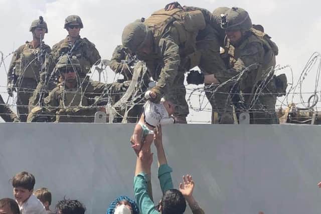 A US Marine lifts a baby over a barbed wire fence at Kabul's international airport as people scrambled to escape the advance of the Taliban in August last year (Picture courtesy of Omar Haidiri/AFP via Getty Images)