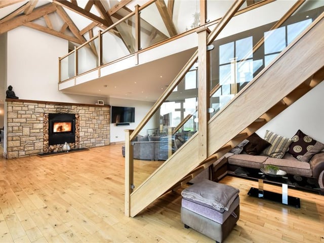 From the siting room, a beautiful contemporary timber staircase with glass balustrades leads up to the galleried landing above.