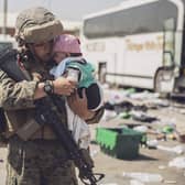 A US Marine carrying a baby as the family processes through the Evacuation Control Center at Hamid Karzai International Airport, Kabul, on Saturday. (Photo by VICTOR MANCILLA/US MARINE CORPS/AFP via Getty Images)