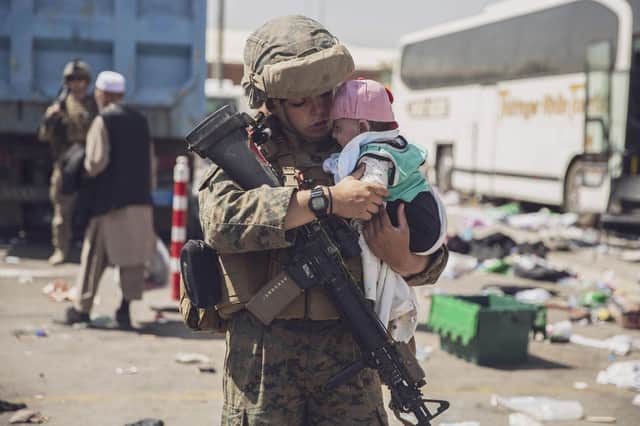 A US Marine carrying a baby as the family processes through the Evacuation Control Center at Hamid Karzai International Airport, Kabul, on Saturday. (Photo by VICTOR MANCILLA/US MARINE CORPS/AFP via Getty Images)