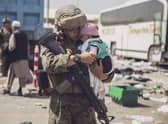 A US Marine carrying a baby as the family processes through the Evacuation Control Center at Hamid Karzai International Airport, Kabul, on Saturday. (Photo by VICTOR MANCILLA/US MARINE CORPS/AFP via Getty Images)