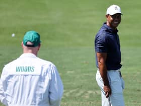 Tiger Woods smiles at caddie Joe LaCava as he warms up ahead of a second practice round prior to the 86th Masters. Gregory Shamus/Getty Images.