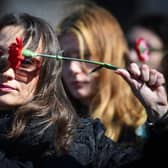 A women holds a flower as she protests against domestic violence in front of the Romanian Ministry of Interior in Bucharest on International Women's Day in 2018. (Photo credit should read DANIEL MIHAILESCU/AFP via Getty Images)