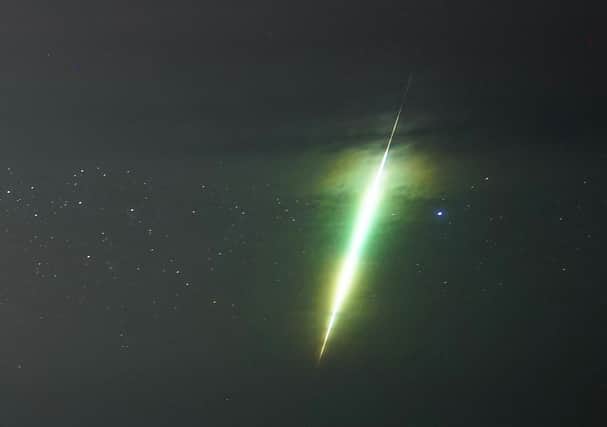 A fisherman watches a meteor during the Draconid meteor shower over Howick rocks in Northumberland.