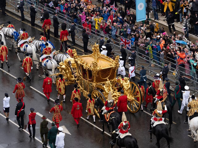 King Charles III and Queen Camilla are carried in the Gold State Coach, pulled by eight Windsor Greys, in the Coronation Procession as they return to Buckingham Palace, London, following their coronation ceremony.