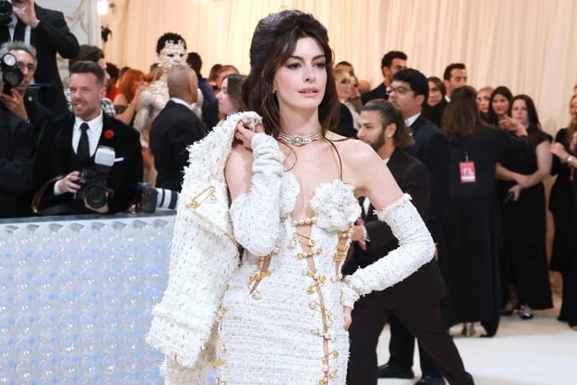 Anne Hathaway wearing a Tweed Versace gown to the 2023 Met Gala which celebrates designer Karl Lagerfeld.