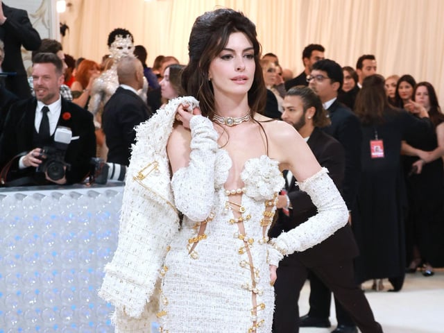 Anne Hathaway wearing a Tweed Versace gown to the 2023 Met Gala which celebrates designer Karl Lagerfeld.