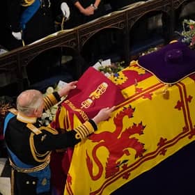 King Charles III places the the Queen's Company Camp Colour of the Grenadier Guards on the coffin during the Committal Service for Queen Elizabeth II held at St George's Chapel in Windsor Castle, Berkshire.