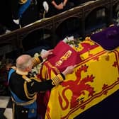 King Charles III places the the Queen's Company Camp Colour of the Grenadier Guards on the coffin during the Committal Service for Queen Elizabeth II held at St George's Chapel in Windsor Castle, Berkshire.