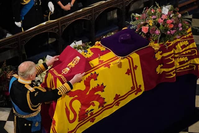 King Charles III places the the Queen's Company Camp Colour of the Grenadier Guards on the coffin during the Committal Service for Queen Elizabeth II held at St George's Chapel in Windsor Castle, Berkshire.