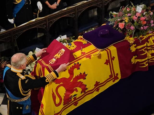 King Charles III places the the Queen's Company Camp Colour of the Grenadier Guards on the coffin during the Committal Service for Queen Elizabeth II held at St George's Chapel in Windsor Castle, Berkshire.
