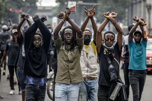 Protesters make signs with their arms in front of Kenyan police officers during a demonstration against tax rises in Nairobi (Picture: Luis Tato/AFP via Getty Images)
