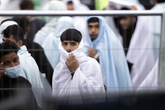 Migrant men wrapped in a blankets are kept behind barriers at the Manston airfield migrant processing centre during a visit by home secretary Suella Braverman. Picture: Dan Kitwood/Getty Images