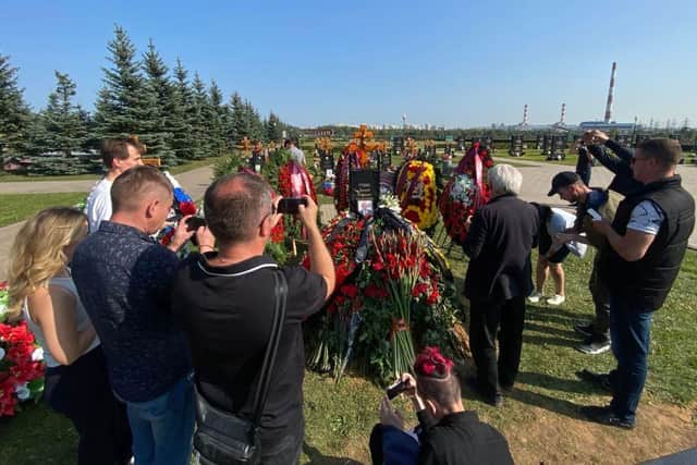 Journalists use their smartphones to take pictures and videos of the grave of Wagner private mercenary group military commander Dmitry Utkin, who was killed in a private jet crash in the Tver region last week, alongside the group's leader, Yevgeny Prigozhin.