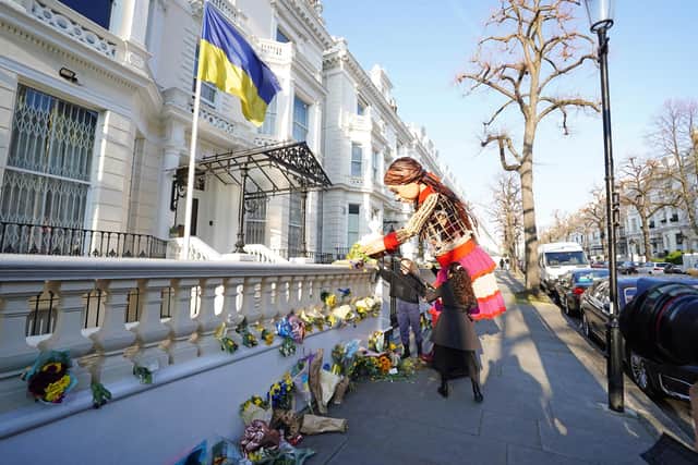 Little Amal, a 3.5-metre partly-animatronic, refugee puppet, lays flowers outside the Ukrainian Embassy in London