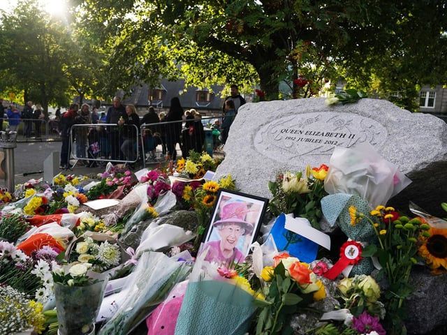 A photo of Queen Elizabeth II left among the flowers laid by members of the public at Balmoral (Pic: PA/Andrew Milligan)