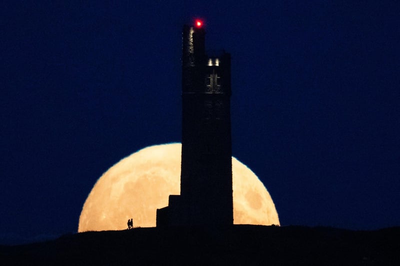 The moon rises behind Victoria Tower on Castle Hill, above Huddersfield. (Photo by Oli SCARFF / AFP)
