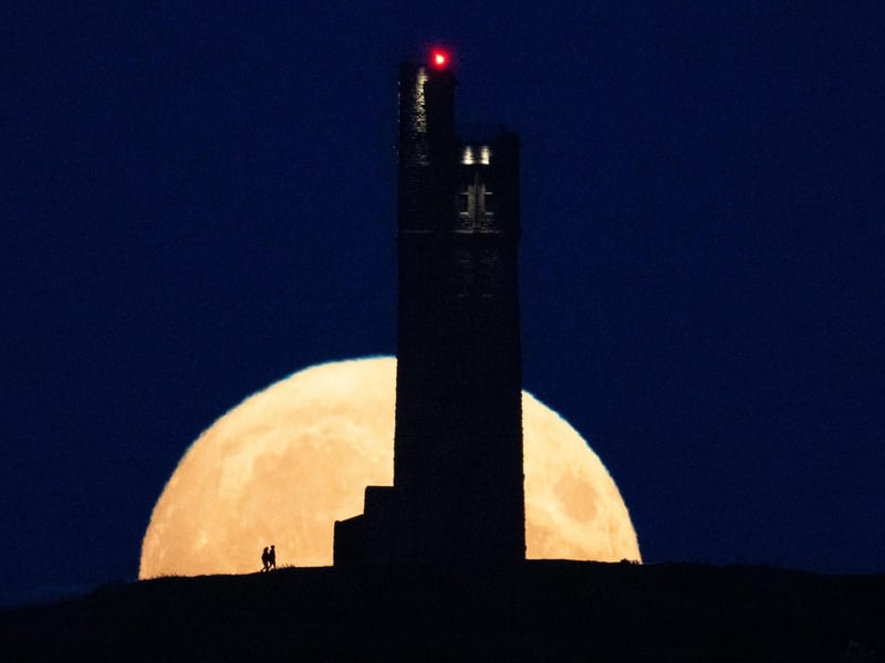 The moon rises behind Victoria Tower on Castle Hill, above Huddersfield. (Photo by Oli SCARFF / AFP)