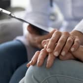 A young nurse wear holds the hand of an elderly person dealing with Alzheimer's disease