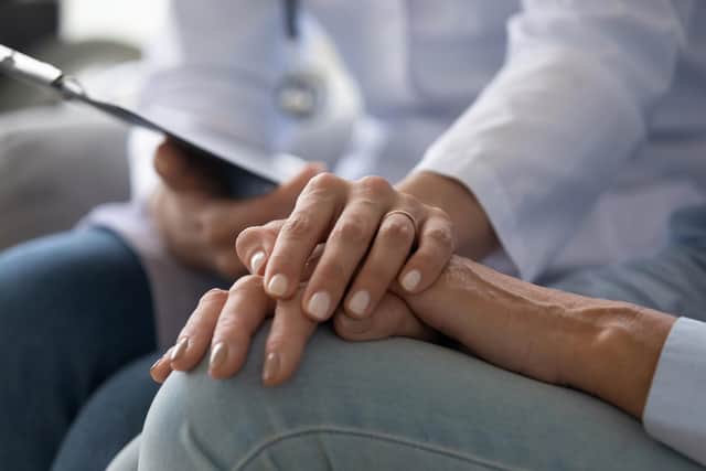A young nurse wear holds the hand of an elderly person dealing with Alzheimer's disease