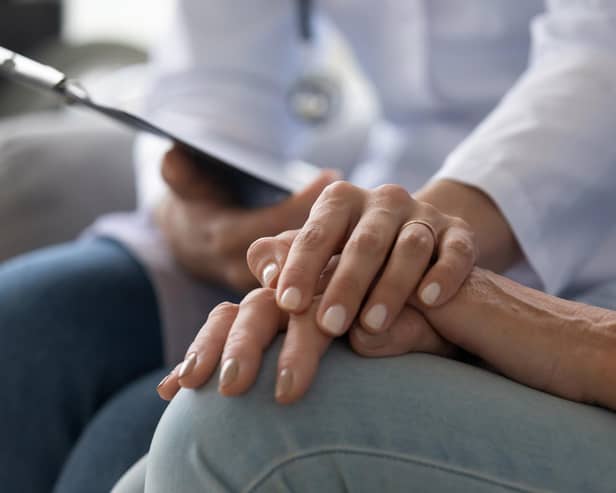 A young nurse wear holds the hand of an elderly person dealing with Alzheimer's disease