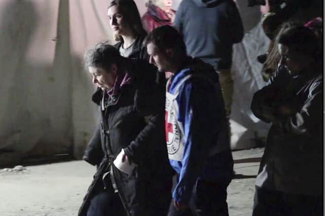 In this photo taken from video, civil evacuees accompanied by Red Cross personnel walk in an area controlled by Russian-backed separatist forces in Bezimenne, about 20 kilometres (12 miles) east of Mariupol, eastern Ukraine, Saturday, April 30, 2022.