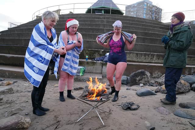 Wild swimmers dry off by the fire after their Christmas Day dip at Portobello. Andrew Milligan/PA Wire