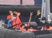 Migrants gesture as they arrive in Dover aboard a Border Force vessel after being intercepted while crossing the English Channel from France in small boats (Picture: Peter Summers/Getty Images)