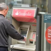 A man using a cash machine outside a branch of Santander in central London. Santander has announced it will be permanently closing 111 branches in the UK picture: John Stillwell/PA