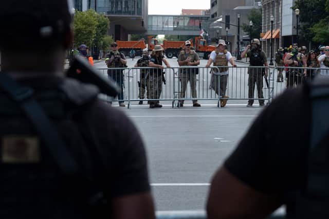 Members of the all-black NFAC militia and the far-right Three Percenters militia face off separated by fences during a rally in Louisville, Kentucky, on Saturday to protest over the killing of Breonna Taylor, a black woman who was shot dead inside her home by police (Picture: Jeff Dean/AFP via Getty Images)
