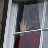 Nicola Sturgeon waves from a window, after holding a press conference, as people gather outside of Bute House. Picture: Jeff J Mitchell/Getty Images