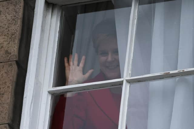 Nicola Sturgeon waves from a window, after holding a press conference, as people gather outside of Bute House. Picture: Jeff J Mitchell/Getty Images