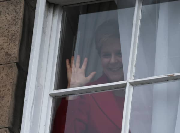 Nicola Sturgeon waves from a window, after holding a press conference, as people gather outside of Bute House. Picture: Jeff J Mitchell/Getty Images